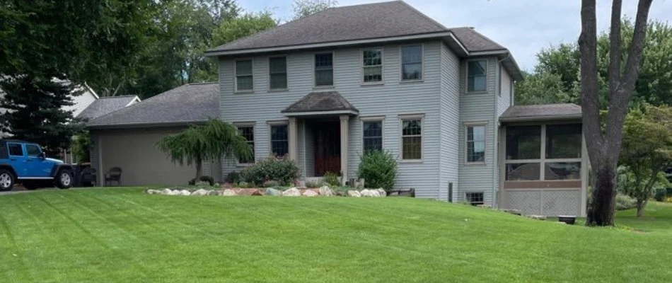 Big house and nice lawn with blue jeep in driveway in Fennville, MI.