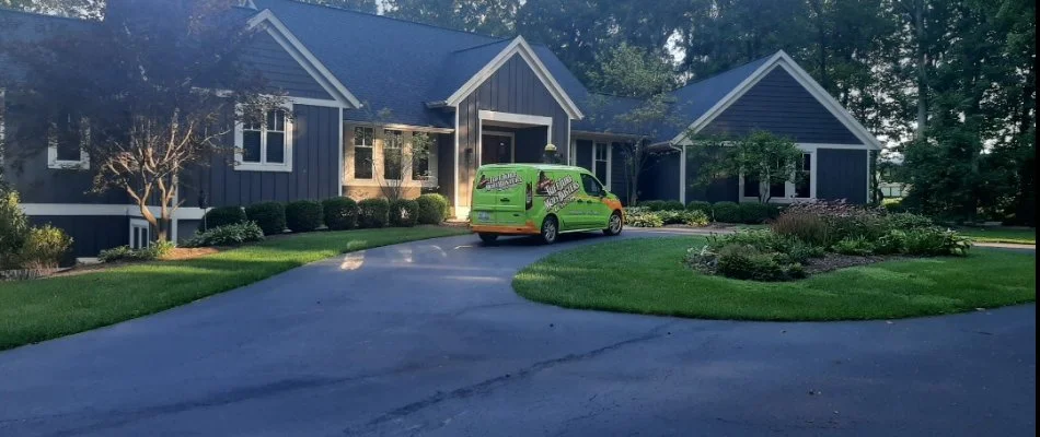 A green van in a driveway in Clarksville, MI, with grass and plants.