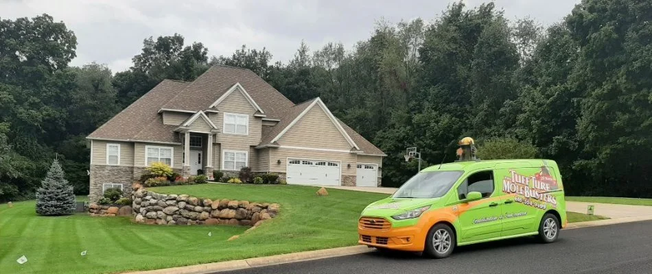 Home in East Grand Rapids, MI, with nice lawn and green van.