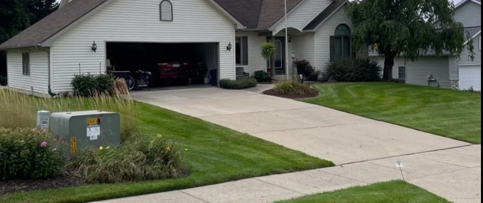 A house in Norton Shores, MI, with a driveway, open garage, and lawn.