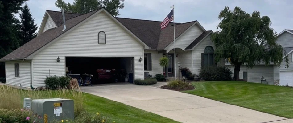 House with open garage in Norton Shores, MI, with a driveway, open garage, and lawn.