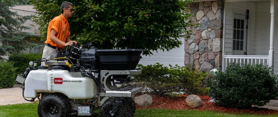 Professional applying a fertilizer treatment to a lawn in West Michigan.