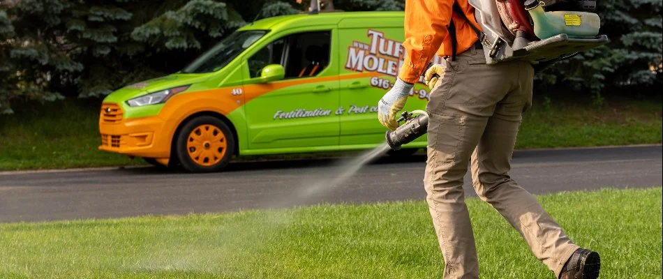Tech fogging grass in Byron Center, MI, and van. 