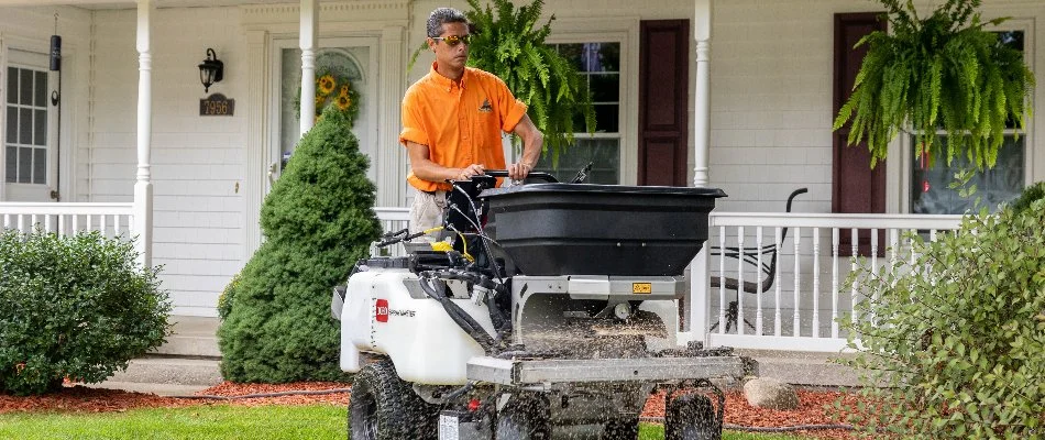 Tech spreading granular fertilizer on grass in Grand Rapids, MI.
