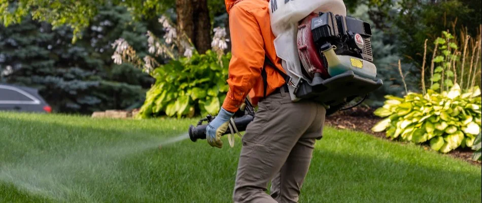 Tech treating a lawn for pests in Hickory Corners, MI, with a backpack fogger.