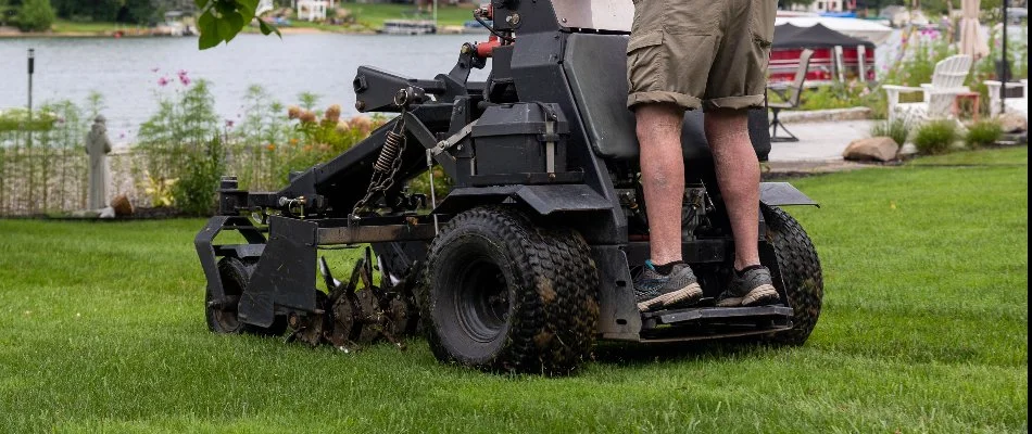 A worker in Parchment, MI, aerating a lawn on an aerator machine.