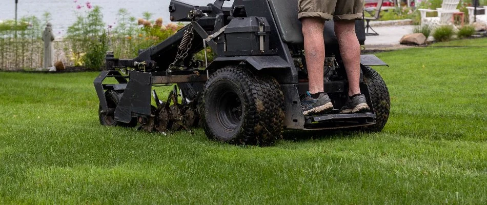 A worker in Grand Rapids, MI, on a core aerator machine.