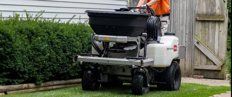 A worker in Augusta, MI, on a granular lawn spreader.