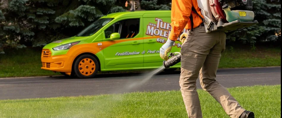 A worker in Allegan, MI, using a backpack fogger to treat a lawn.